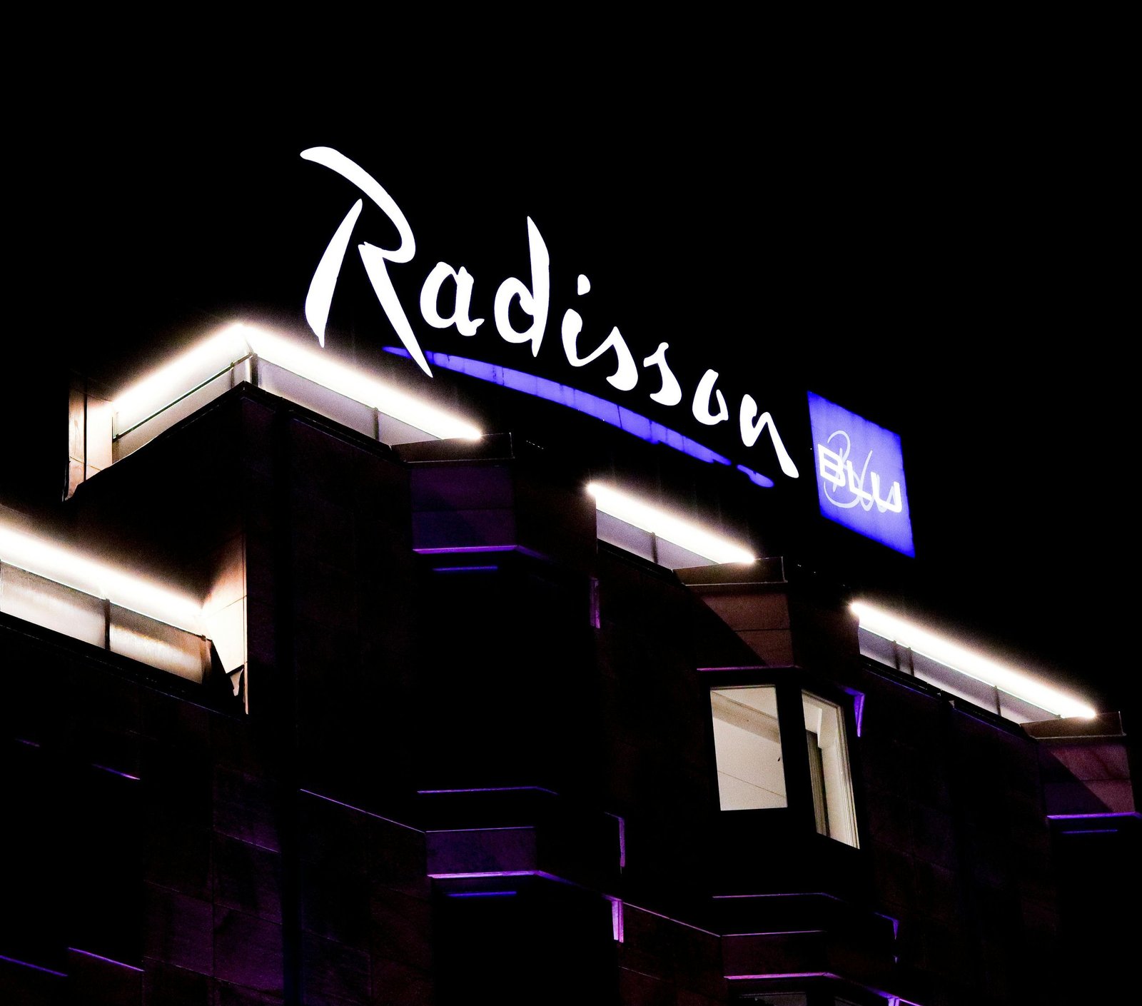 Illuminated script logo sign on a hotel facade