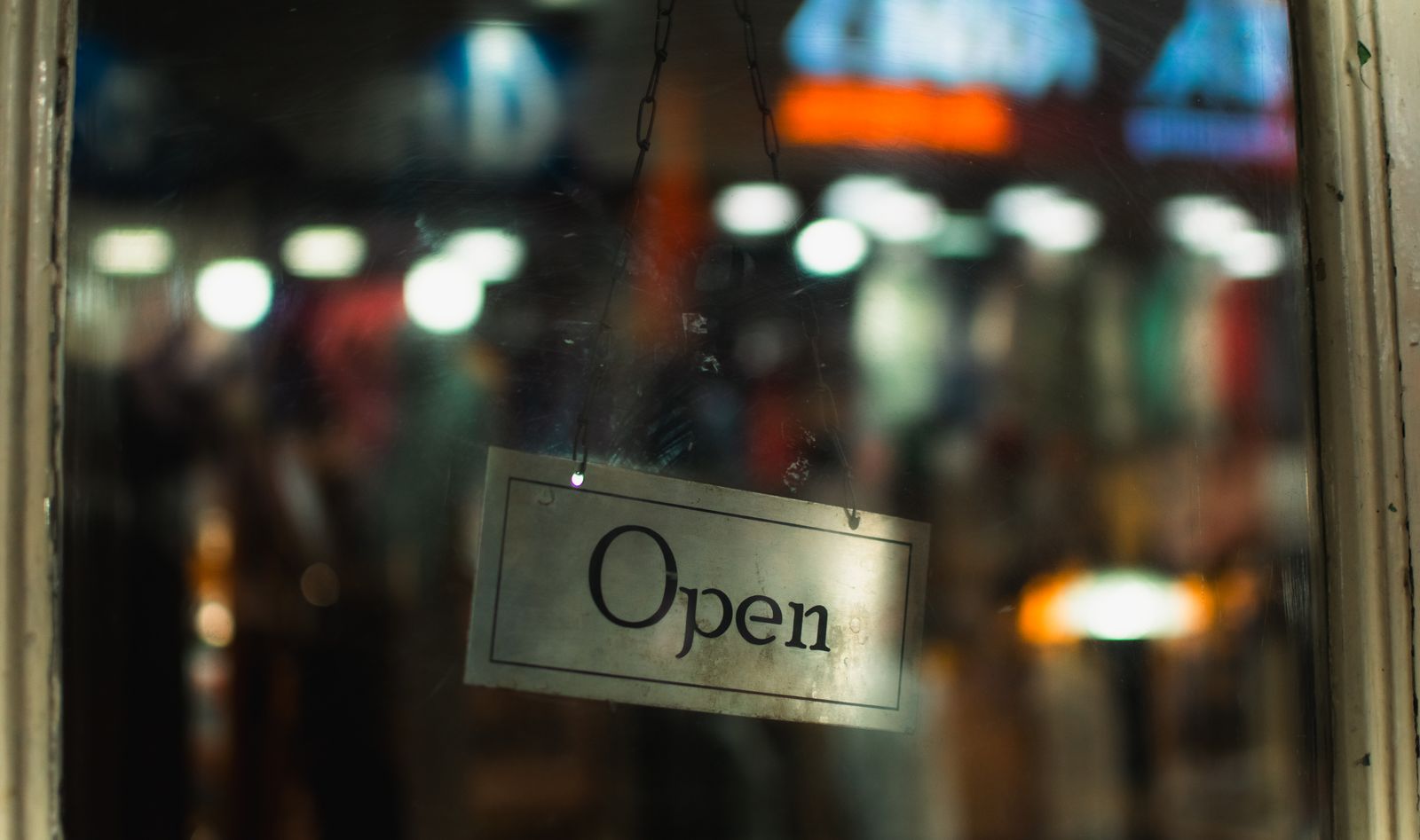 Illuminated open sign viewed through a storefront window